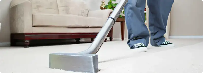 Carpet cleaning technician using a hot-water extraction wand on a light-colored carpet in a living room, Honolulu, HI.